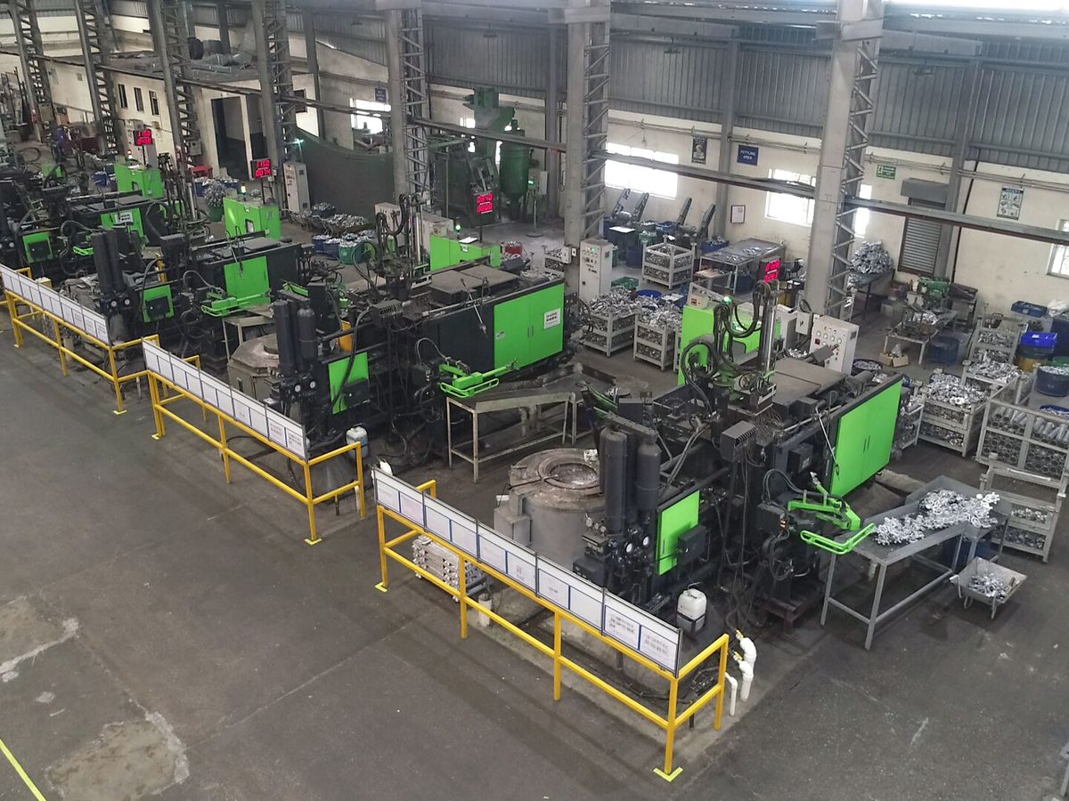 Line of high pressure die casting machines with safety railings and cast parts in trays